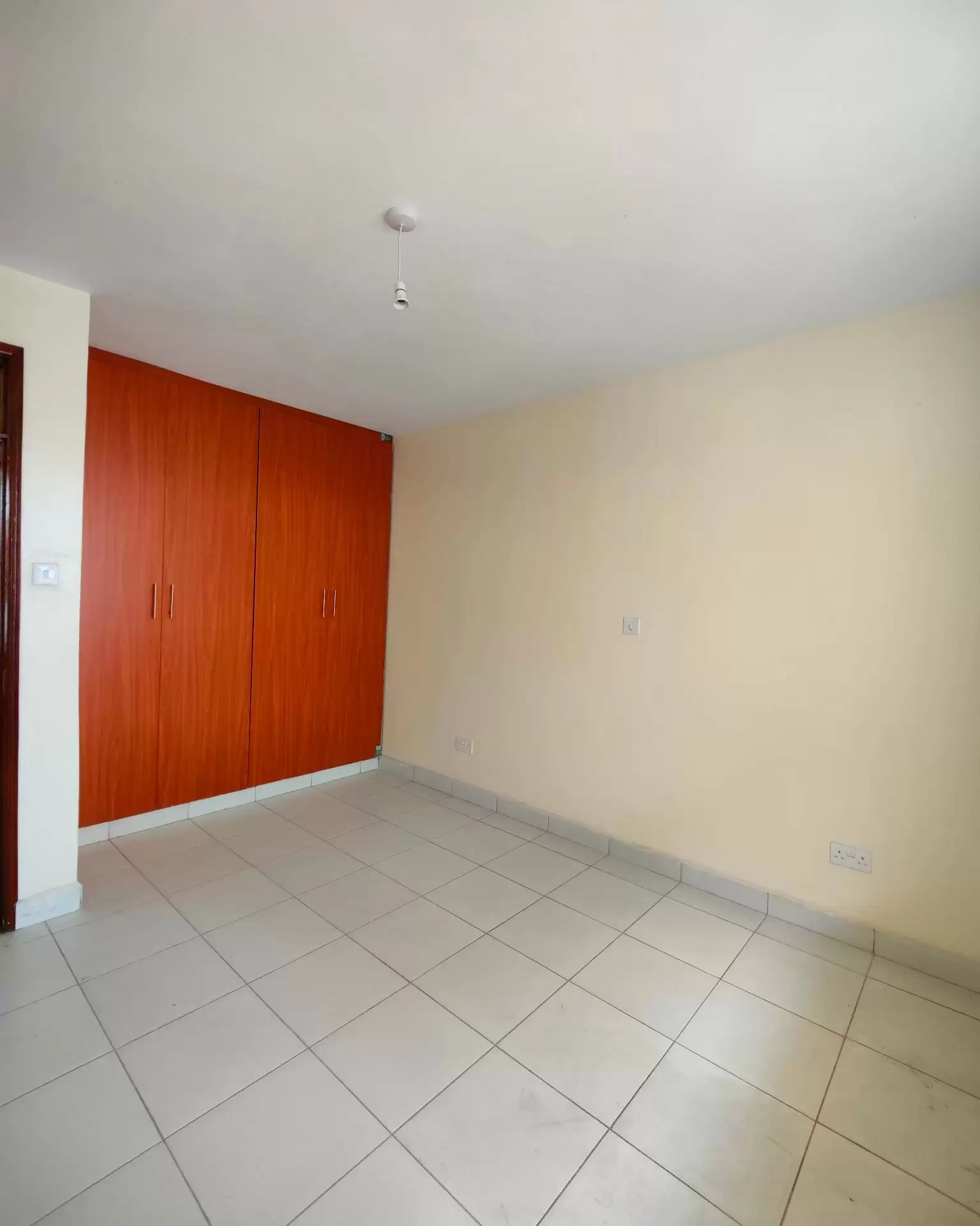Unfurnished bedroom with red wardrobe and tiled floor