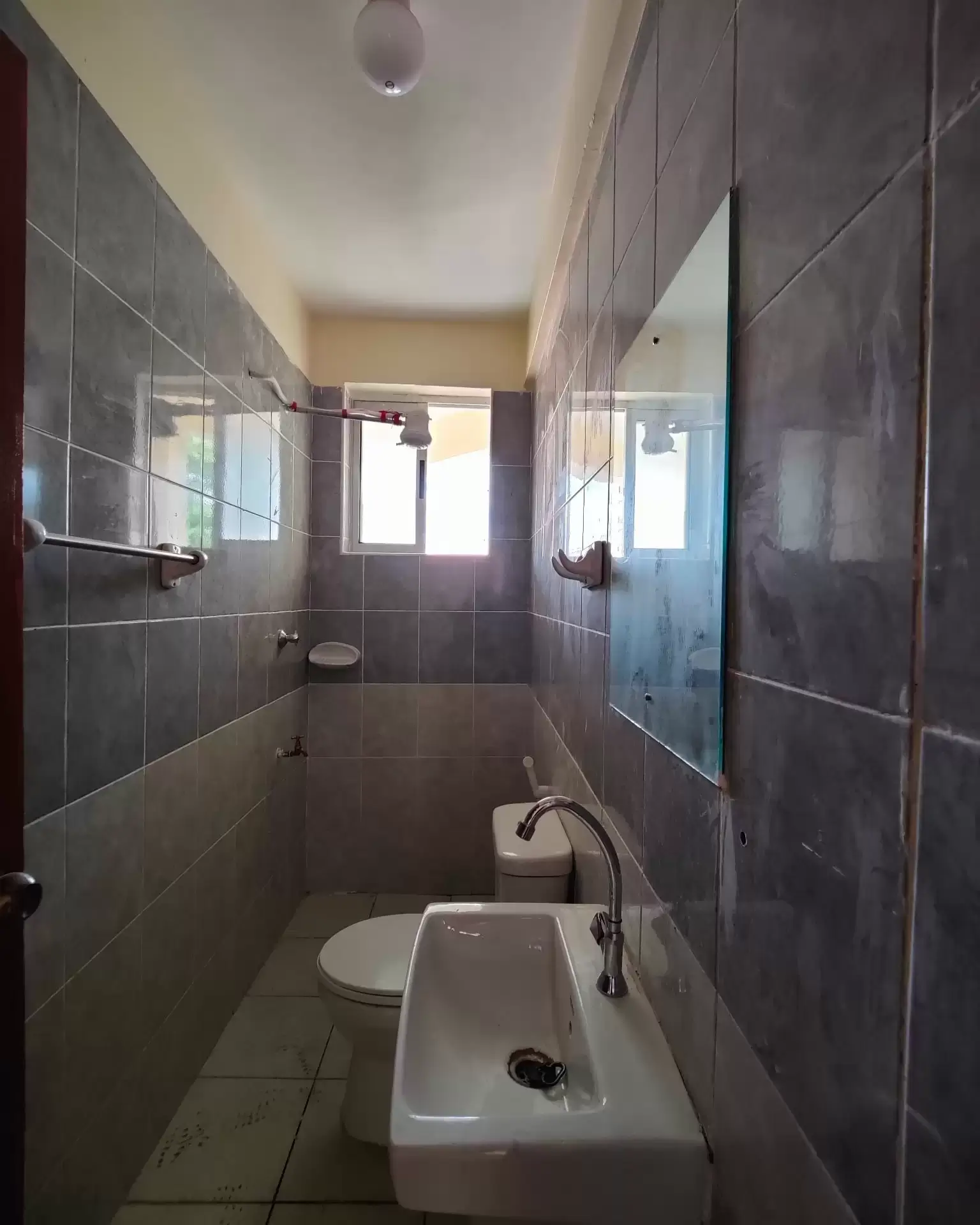 Narrow bathroom with dark tile walls and white sink
