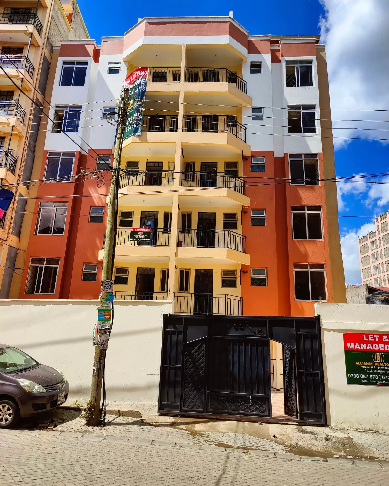 Colorful multi-story residential building with balconies and parking entrance