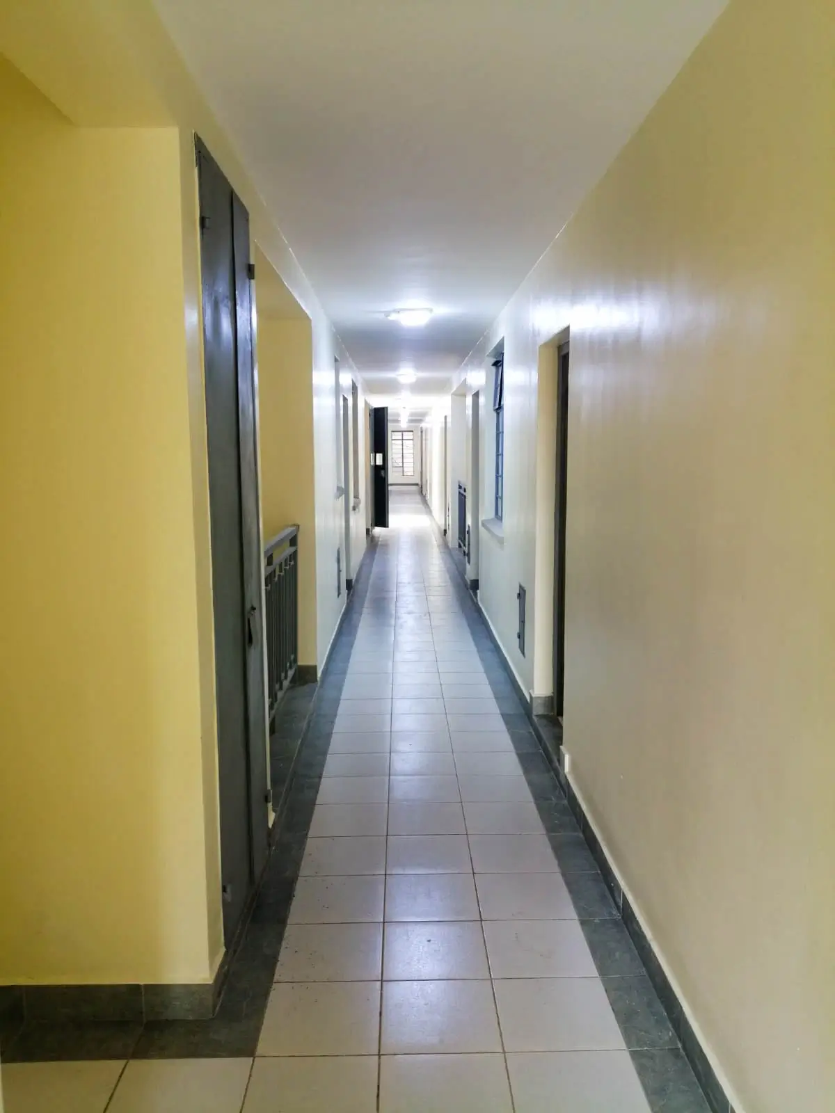 Long corridor with yellow walls and tiled flooring