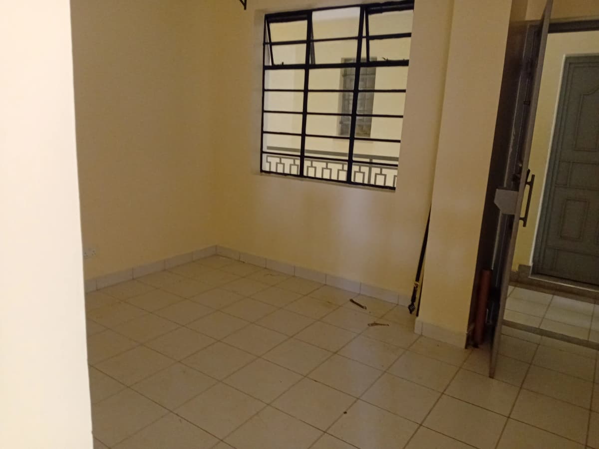 Empty bedroom with tiled floor and barred window