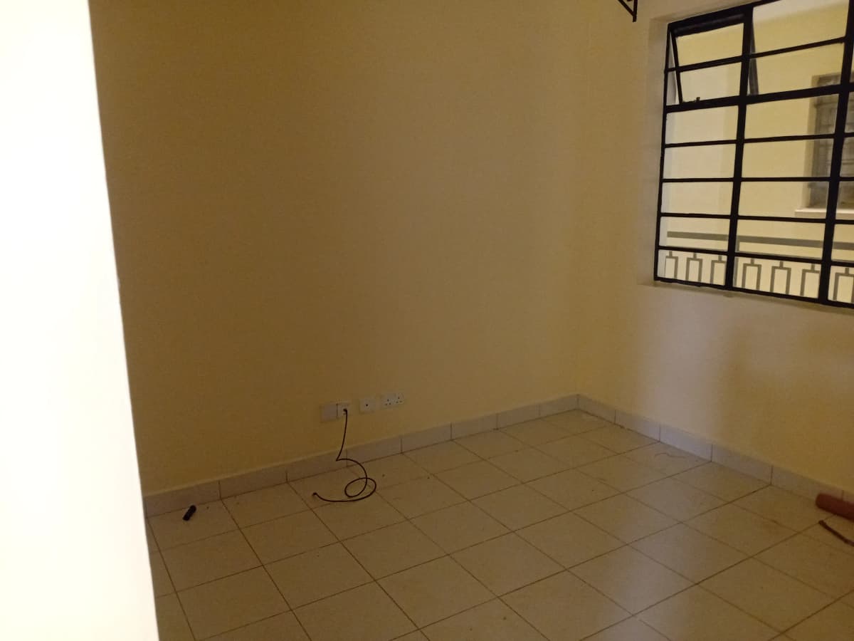 Empty bedroom with tiled floor and barred window