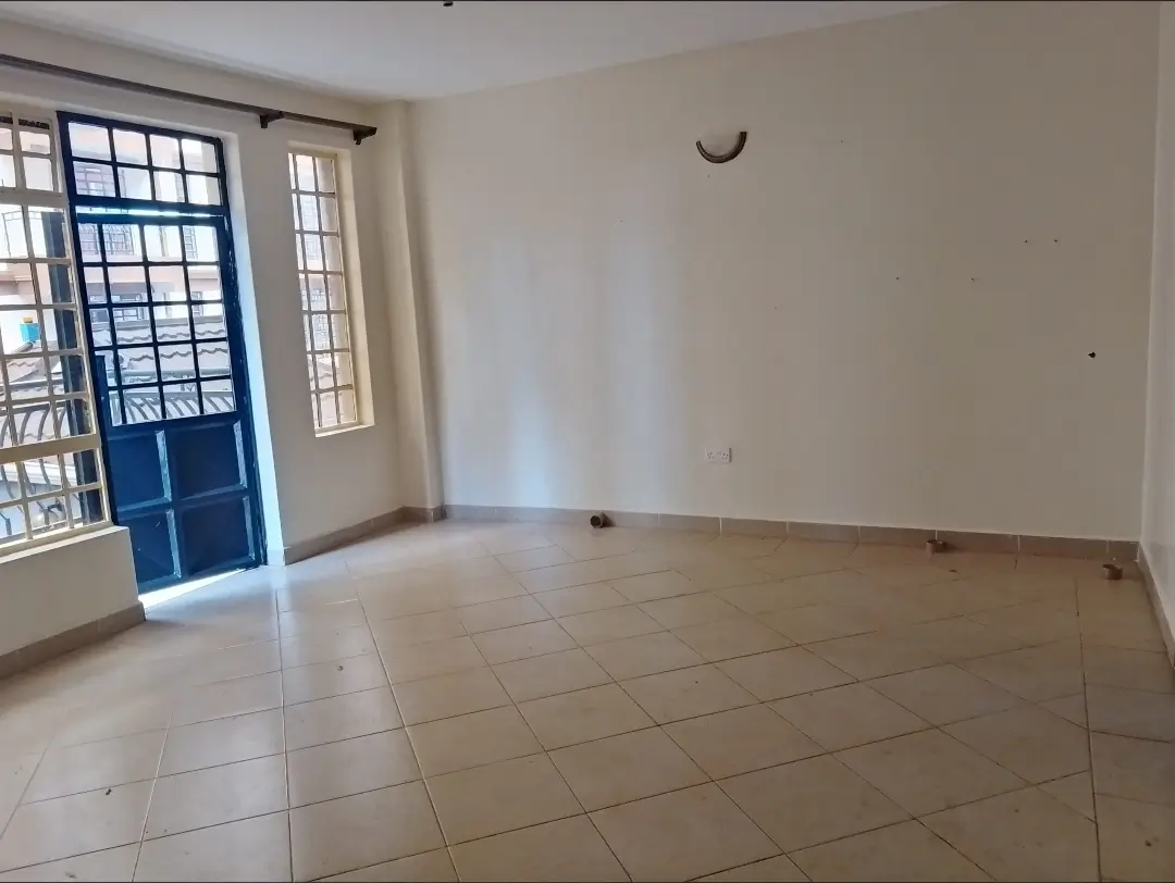 Spacious empty living room with tiled floors and glass door