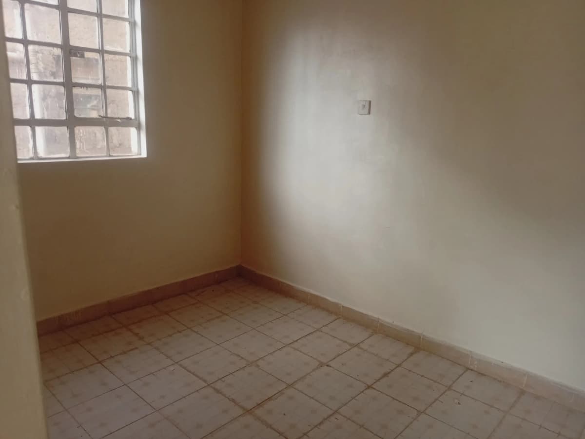 Empty bedroom with tiled floor and barred window