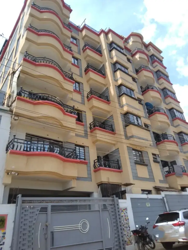 Multi-story residential building facade with balconies and ground-level parking