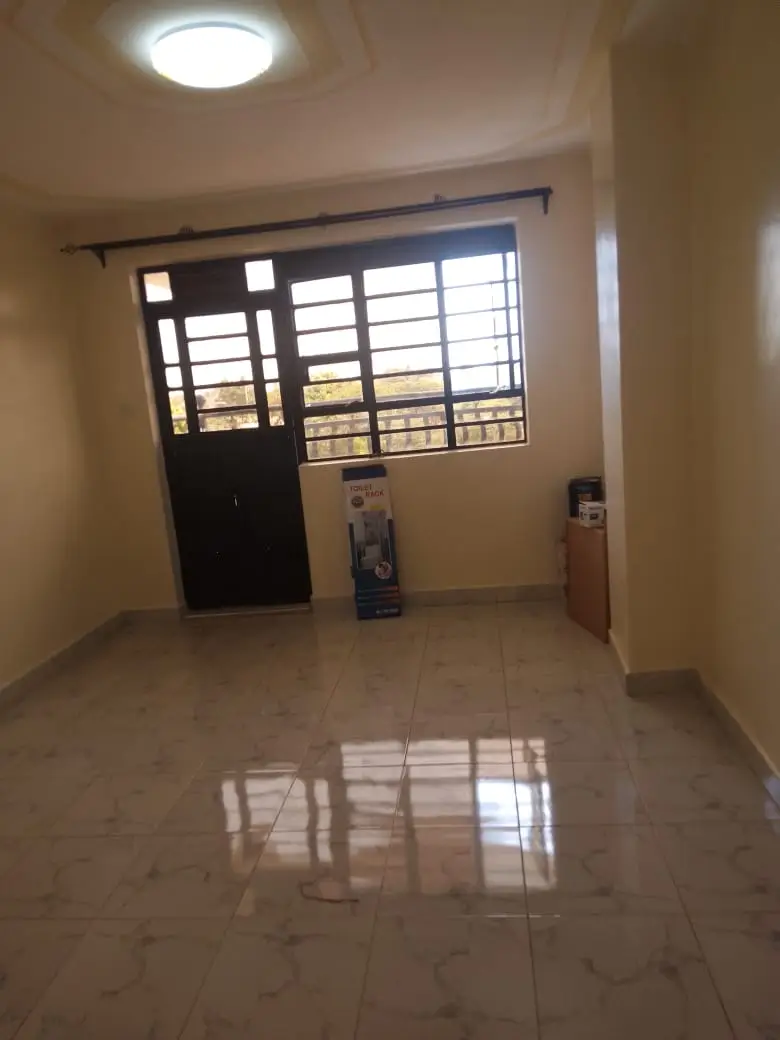 Empty living room with barred window and polished tile flooring