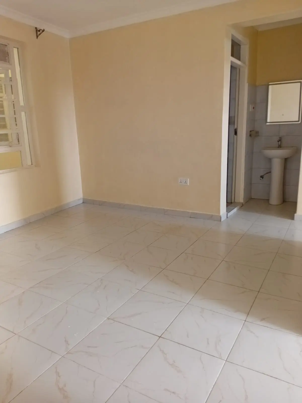 Empty bedroom with en-suite bathroom visible through doorway