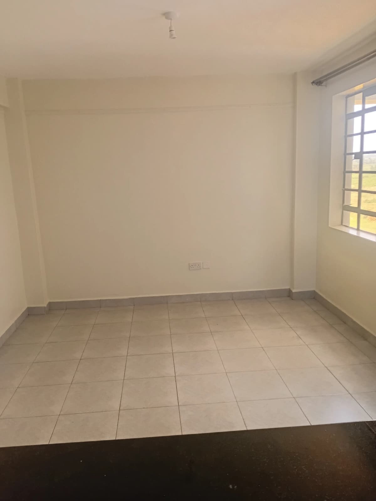 Empty bedroom with tiled floor and natural window light