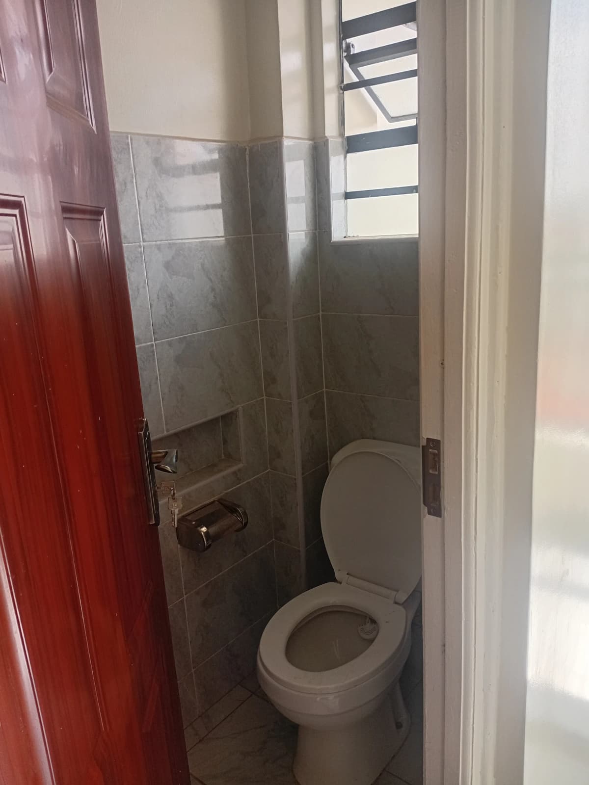Compact bathroom with toilet, shower enclosure, natural light