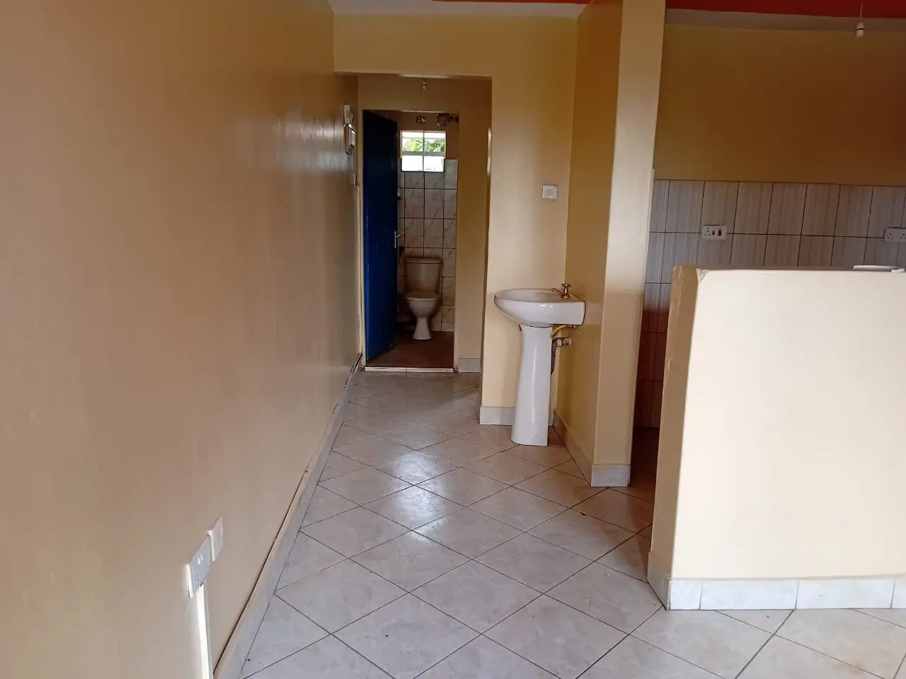 Bathroom with pedestal sink and toilet, tiled flooring
