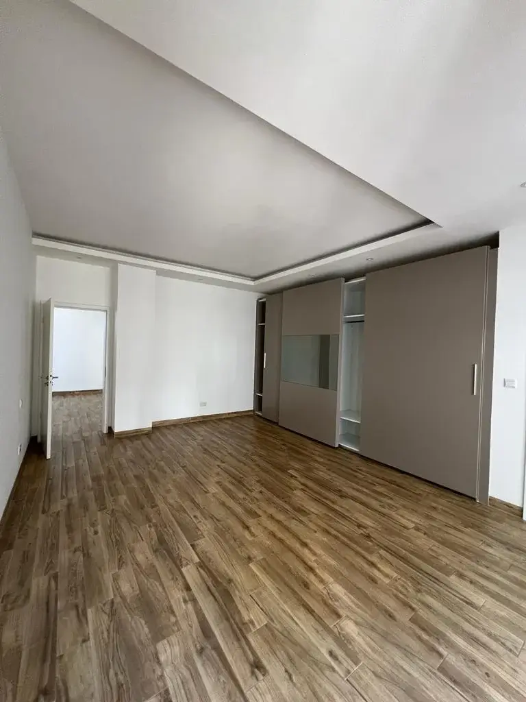 Spacious empty living room with wooden flooring and modern ceiling