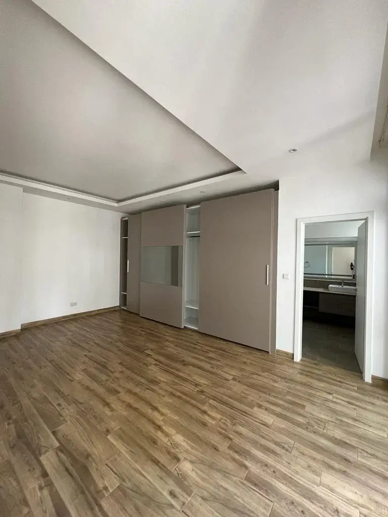 Spacious bedroom with wooden flooring and built-in wardrobes