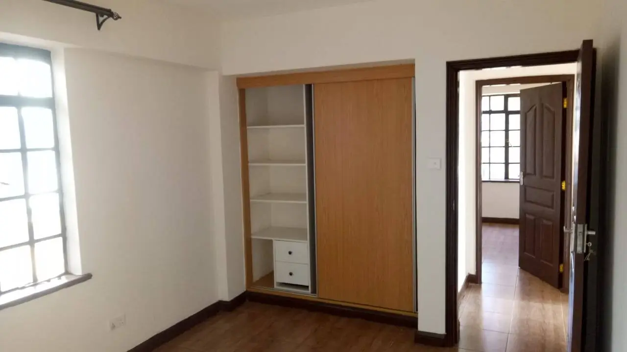 Spacious bedroom with built-in wooden wardrobe and window