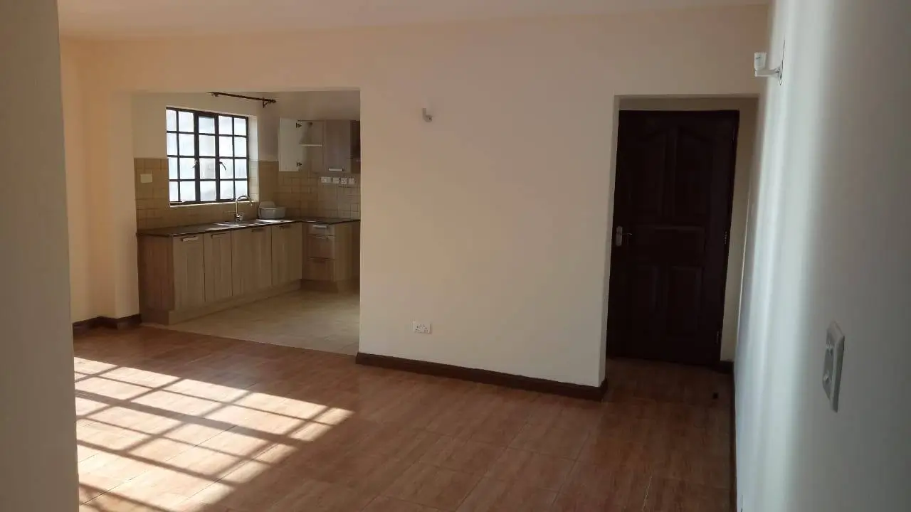 Open-plan living room with kitchen visible through partition