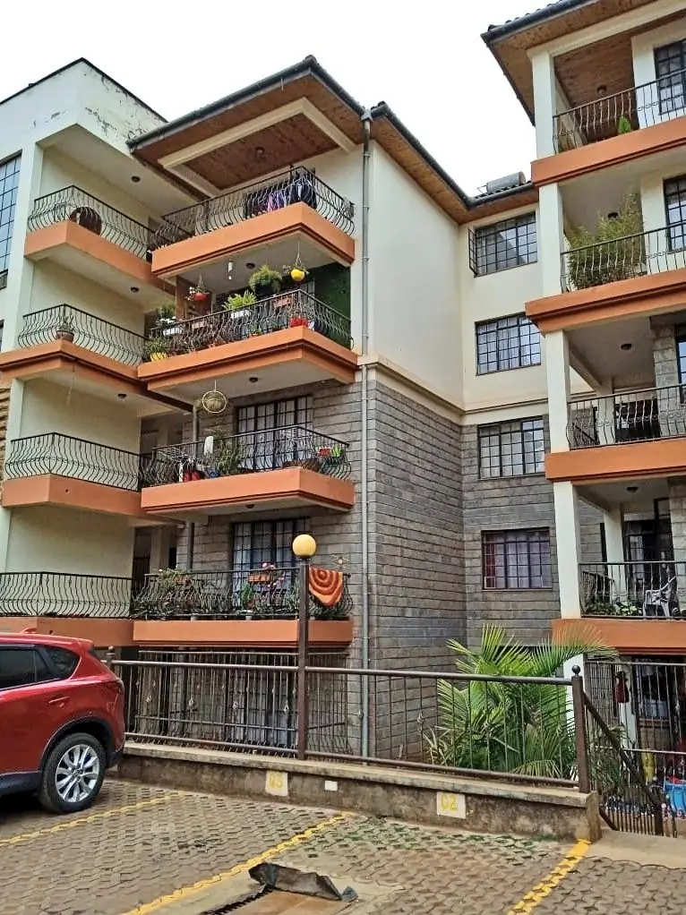 Multi-story residential building with orange balconies and parking