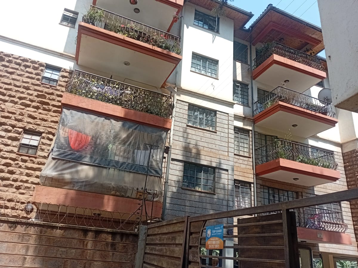 Multi-story residential building with red balconies and brick facade