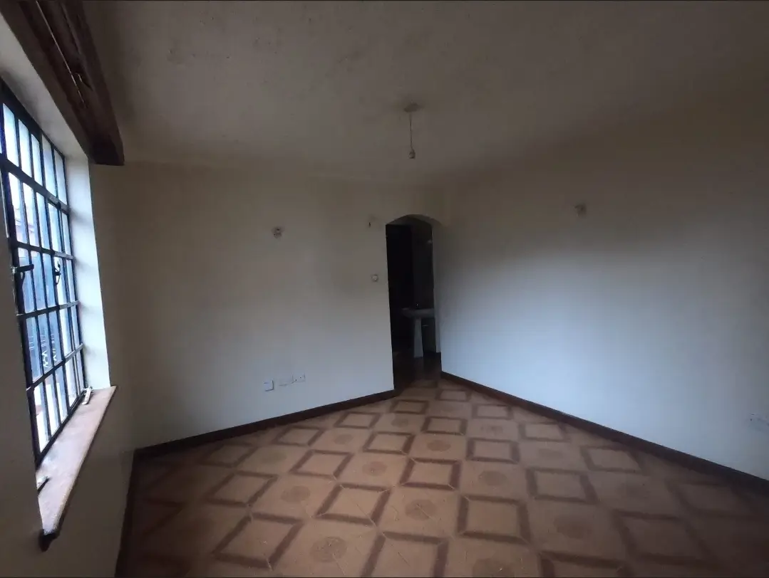 Empty bedroom with geometric tile flooring and barred window