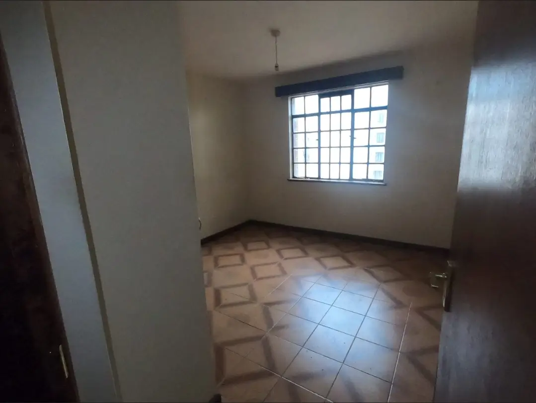 Empty bedroom with tiled floor and barred window