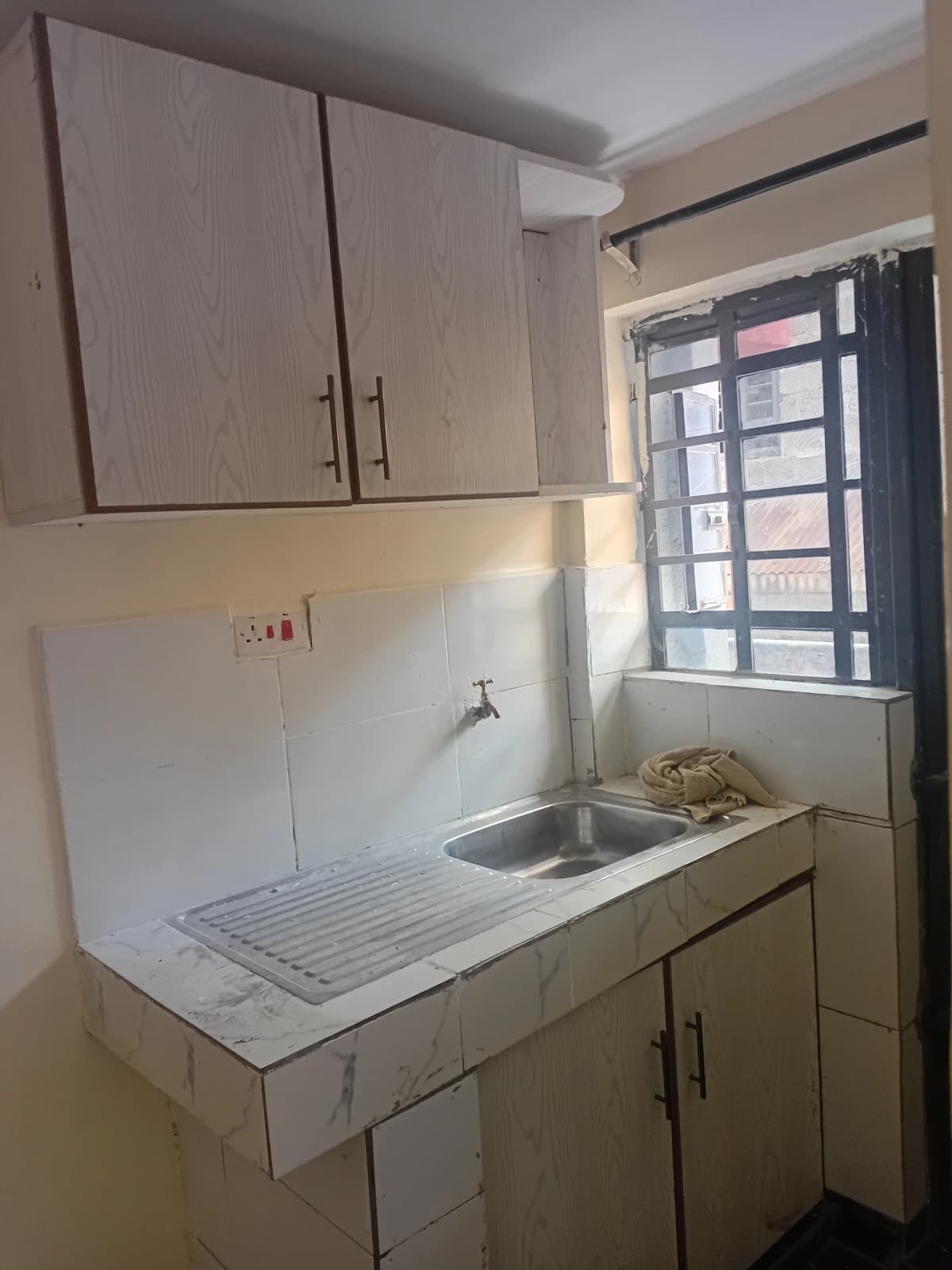 Compact kitchen with sink, drainboard, and overhead storage cabinets