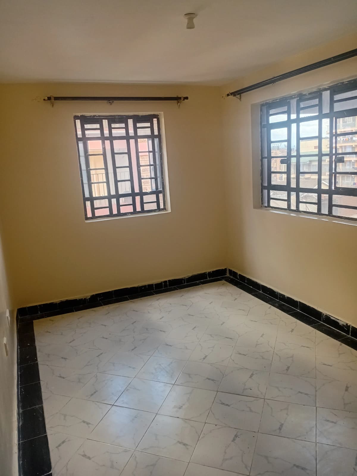 Empty bedroom with yellow walls and barred windows