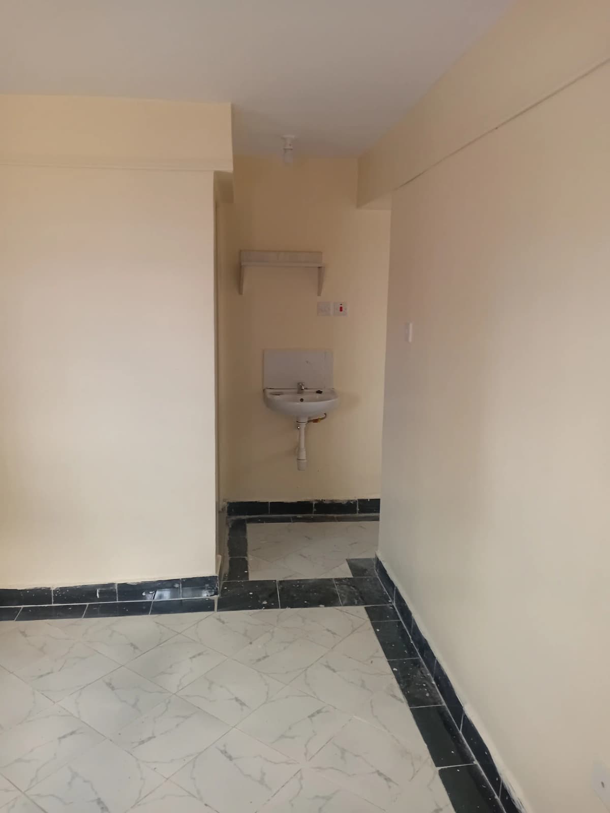 Narrow bathroom with wall-mounted sink and black tile border