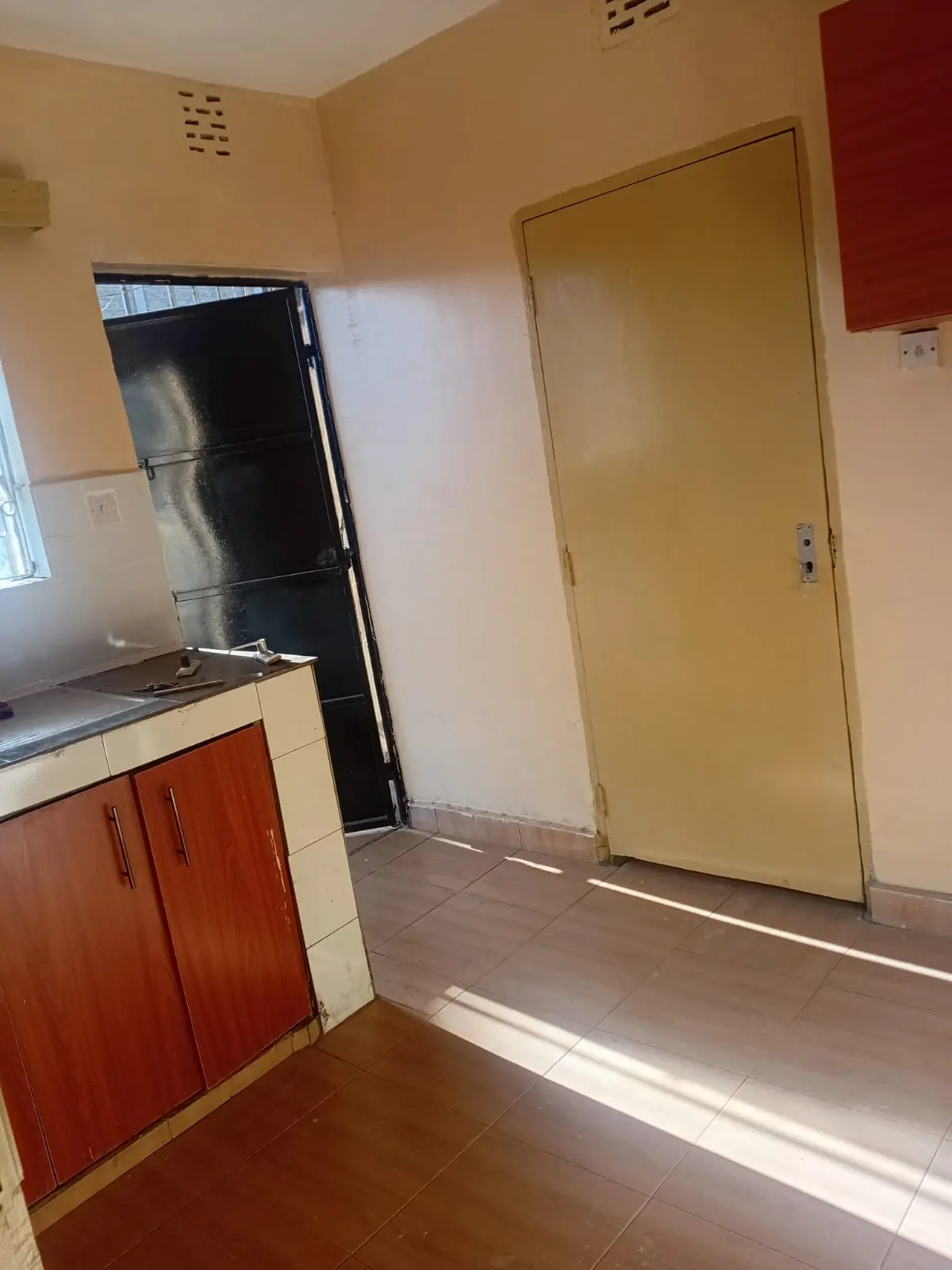 Compact kitchen with red cabinetry and black refrigerator