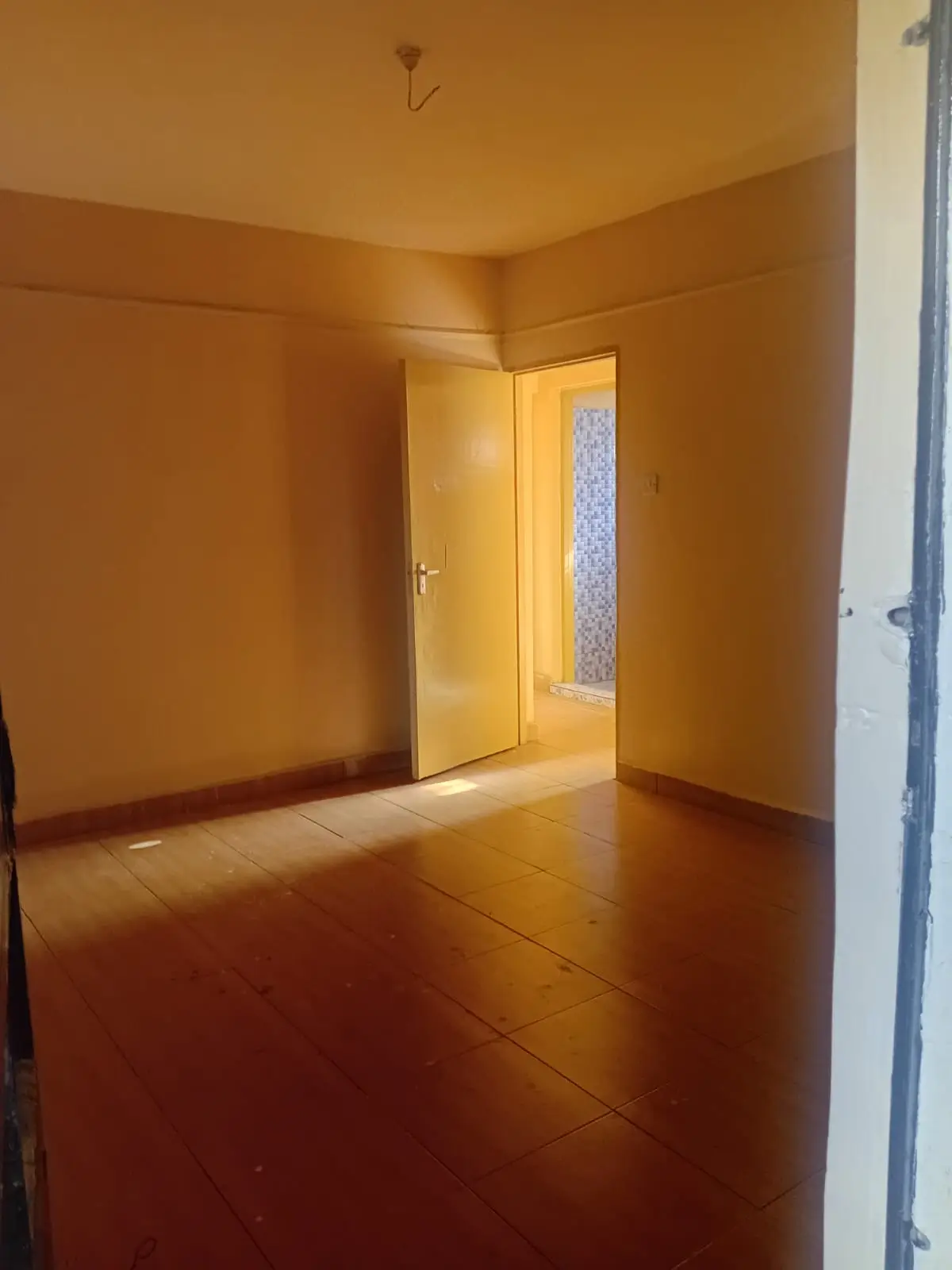 Empty bedroom with warm yellow walls and polished floor