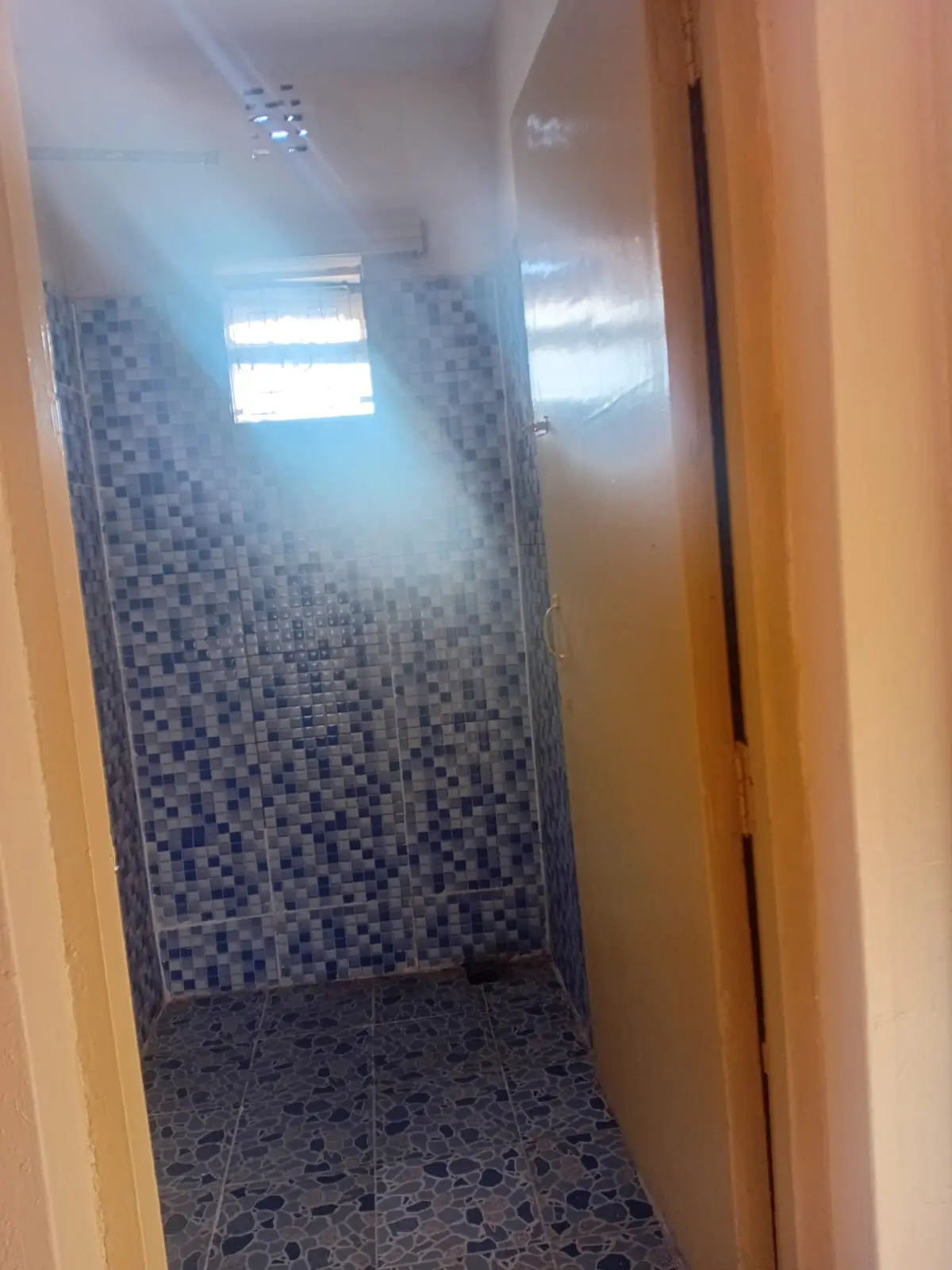 Narrow bathroom with blue mosaic tile walls and window