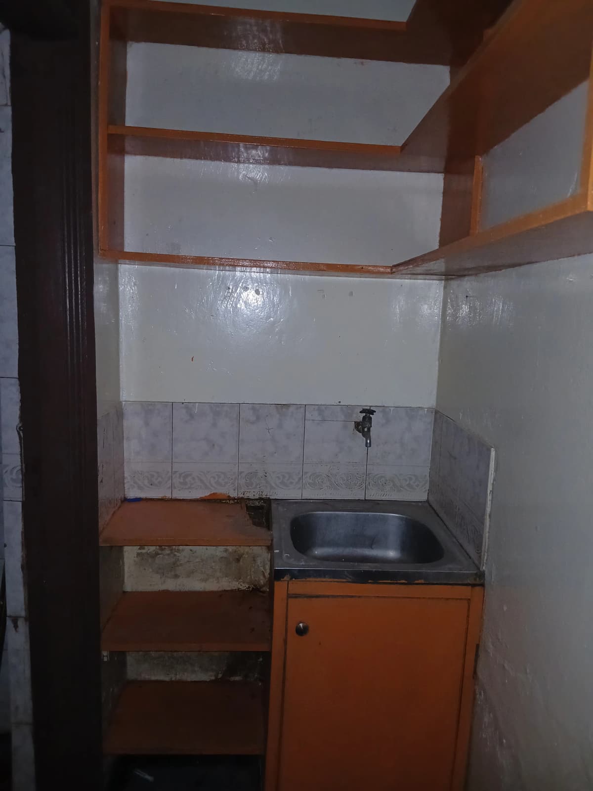 Compact kitchen with orange cabinet and basic sink setup