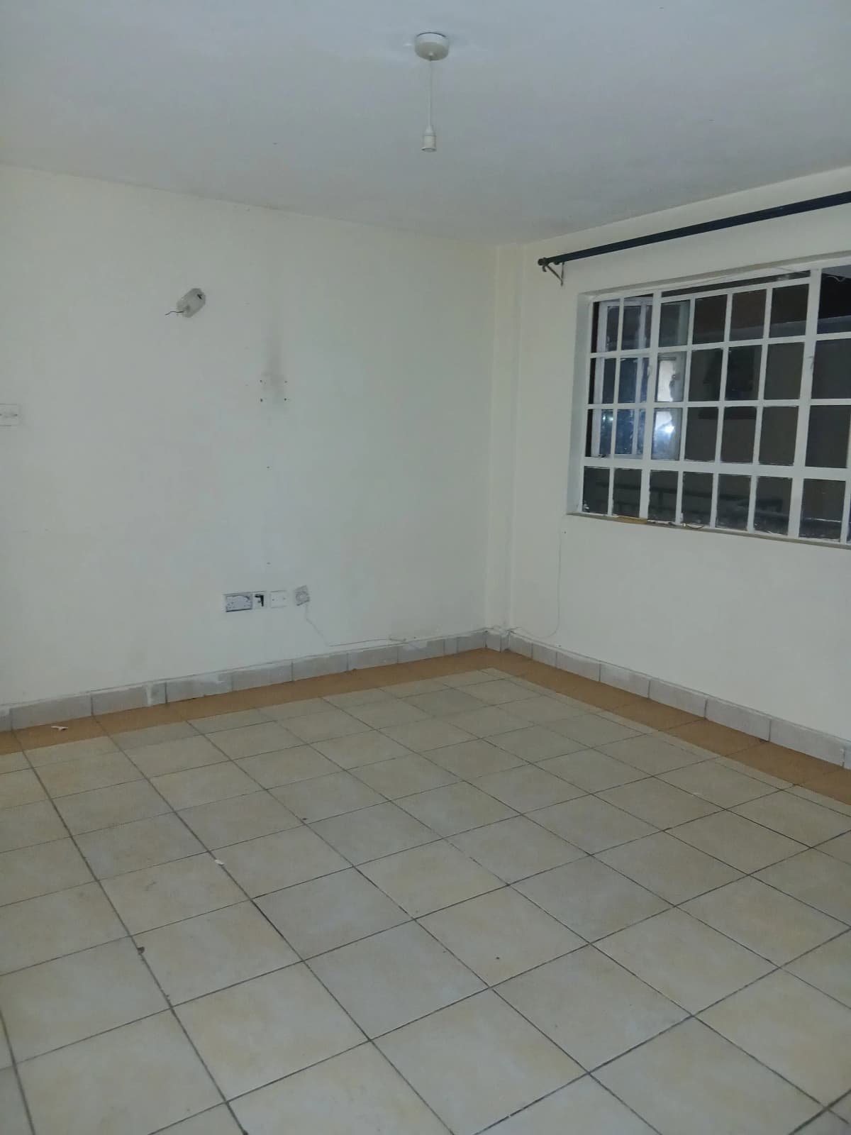Empty bedroom with tiled floor and barred window