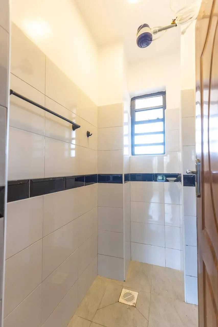 Modern shower enclosure with white tile and blue accent stripe