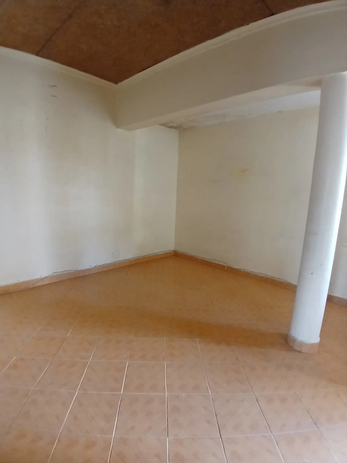 Empty living space with wooden flooring and support column