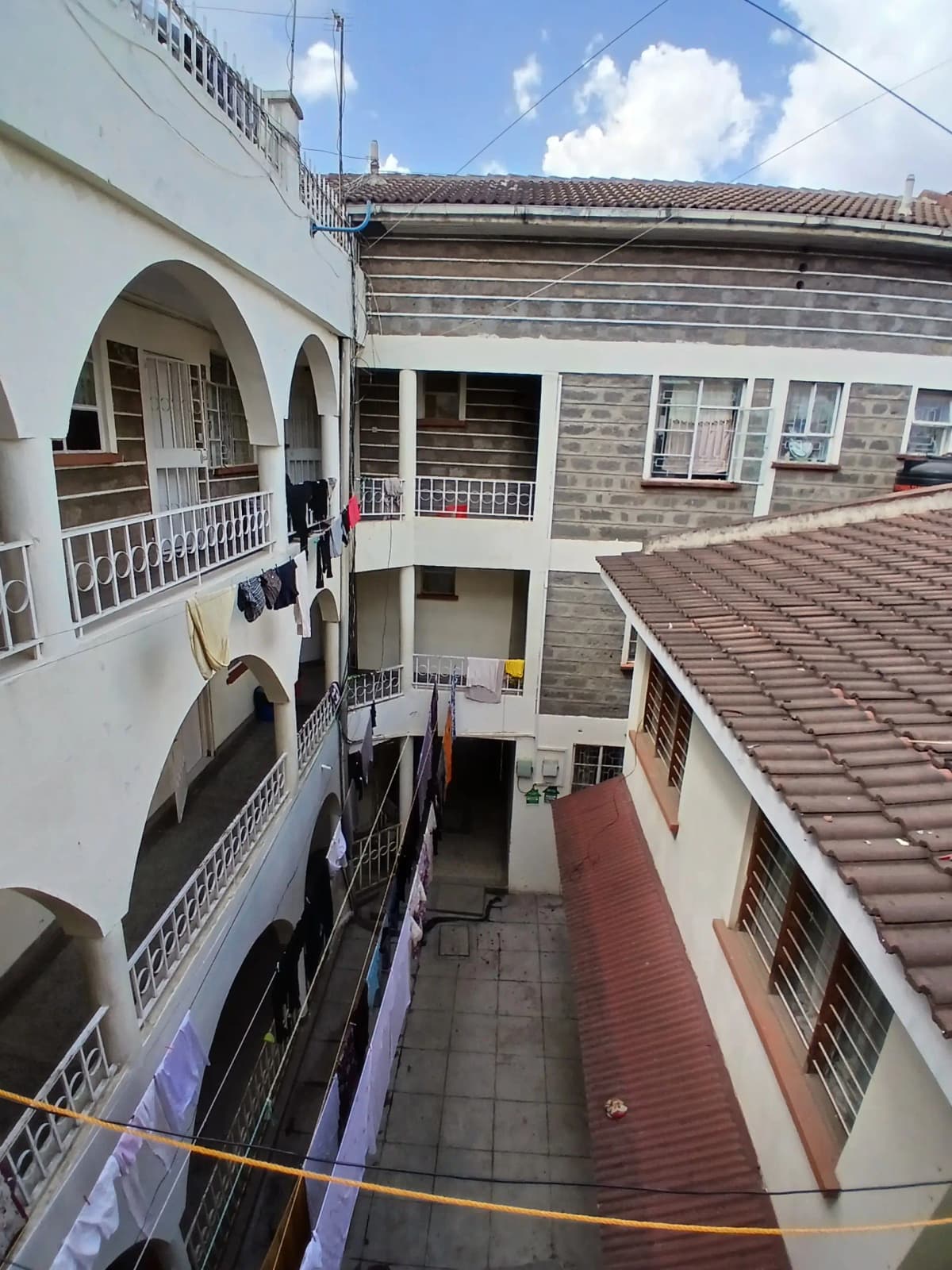 Compound courtyard with red-tiled roofing and neighboring buildings