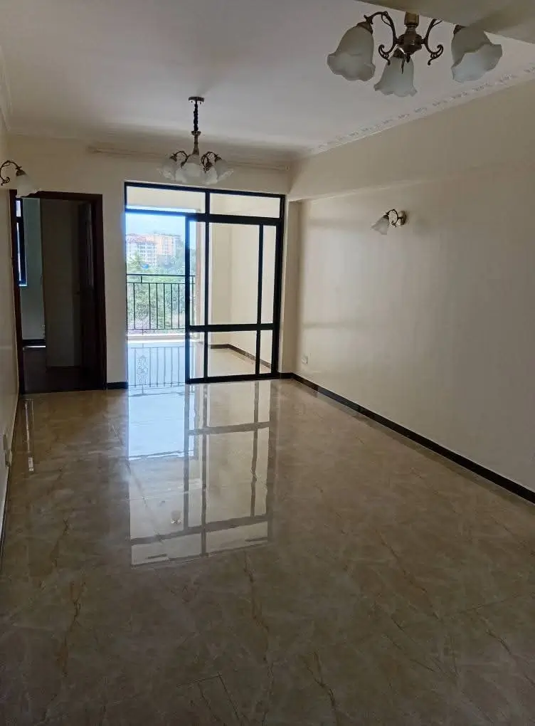 Spacious empty living room with polished flooring and balcony access