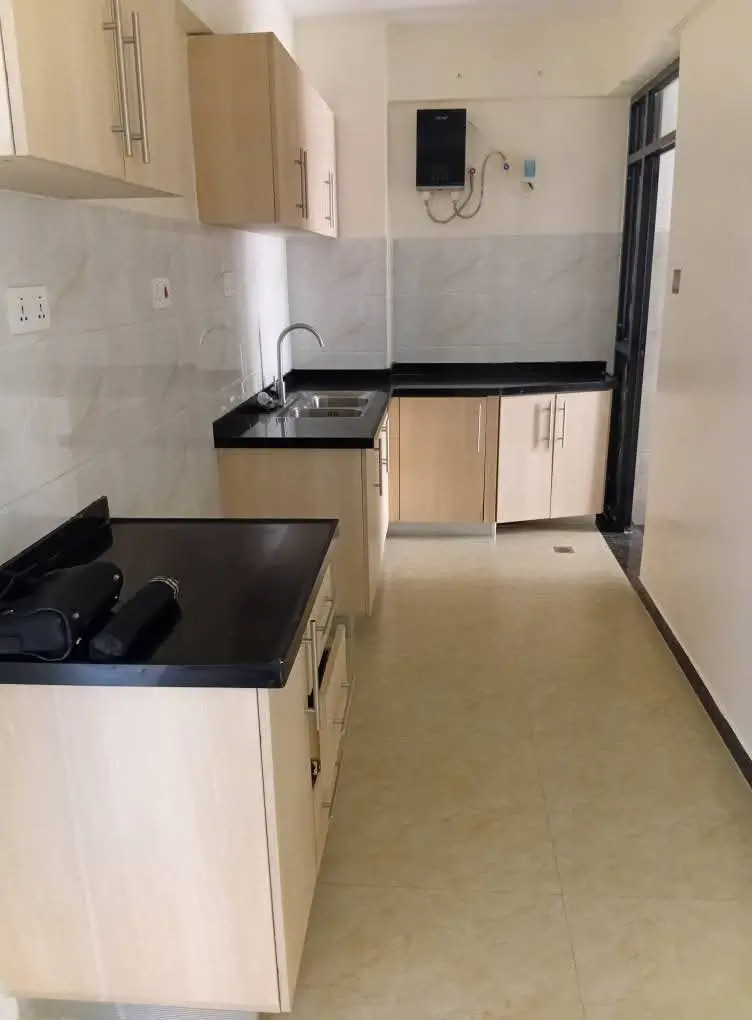 Compact galley kitchen with black countertops and cream cabinets