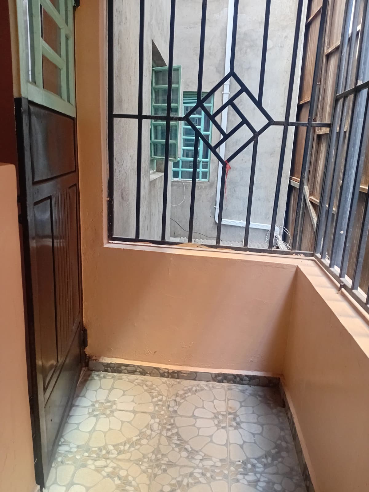 Small enclosed balcony with barred windows and tiled floor