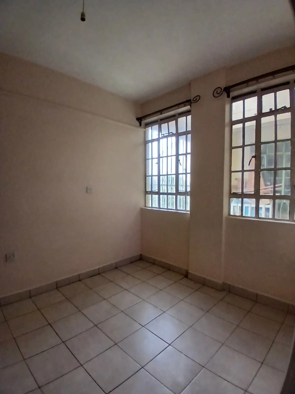 Unfurnished bedroom with barred windows and tiled floor