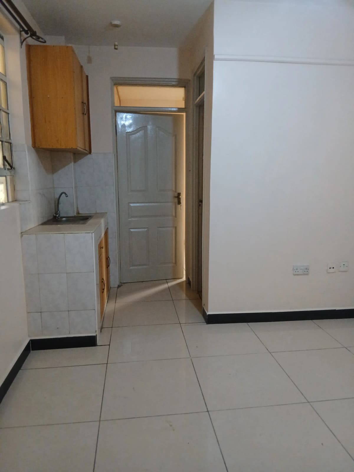 Compact kitchen with small sink, wooden cabinet, tiled floor