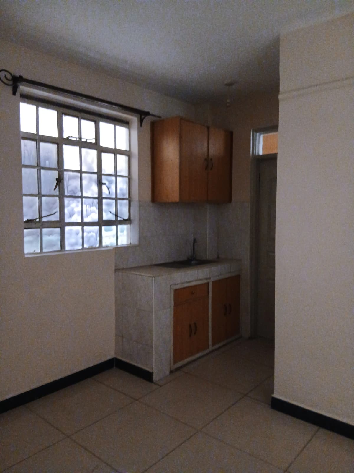 Compact kitchen with wooden cabinets and tile flooring