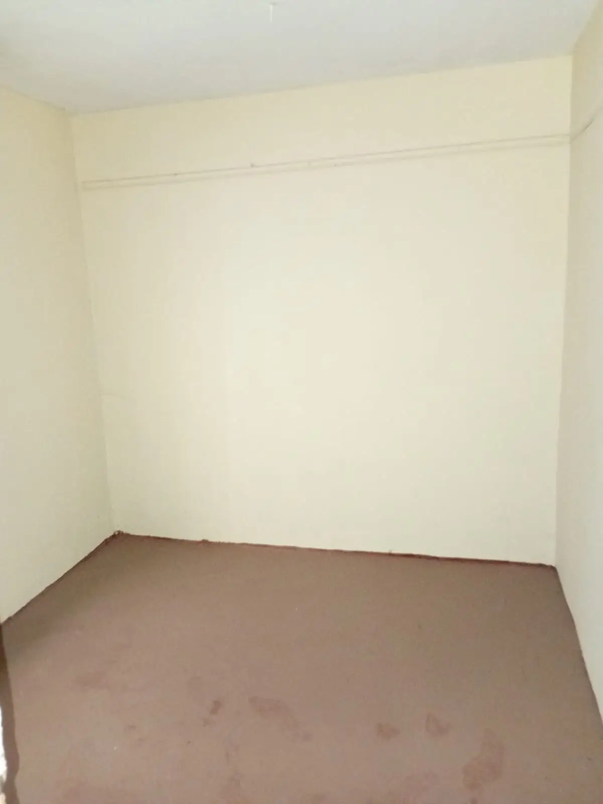 Empty bedroom with cream walls and brown flooring