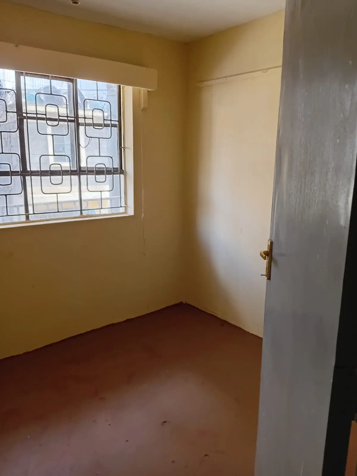 Compact bedroom with yellow walls and barred window