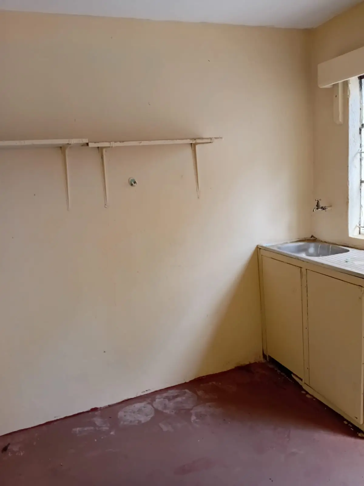 Utility room with sink, clothes rail, and burgundy floor