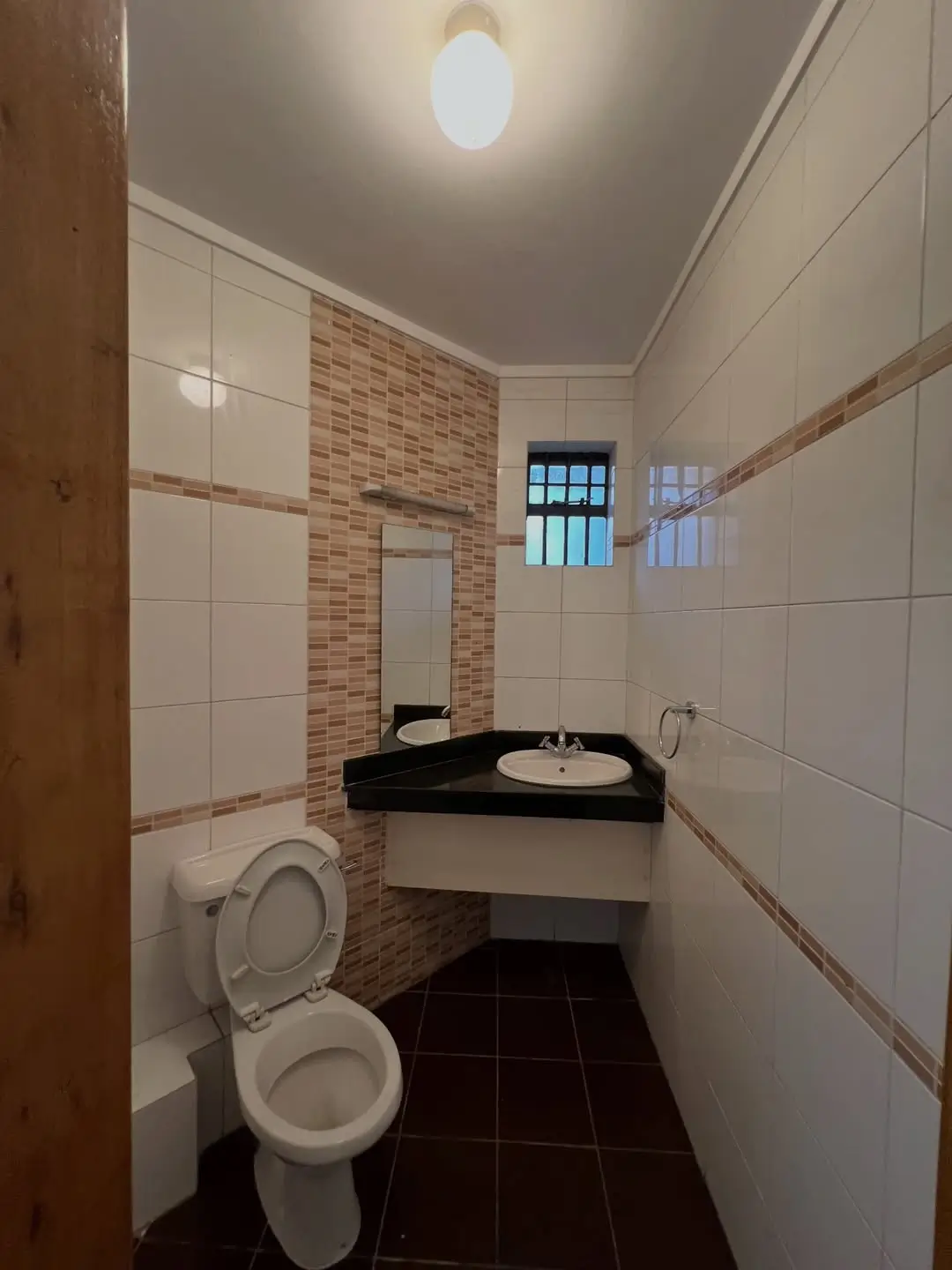 Compact bathroom with toilet, sink, brick accent wall
