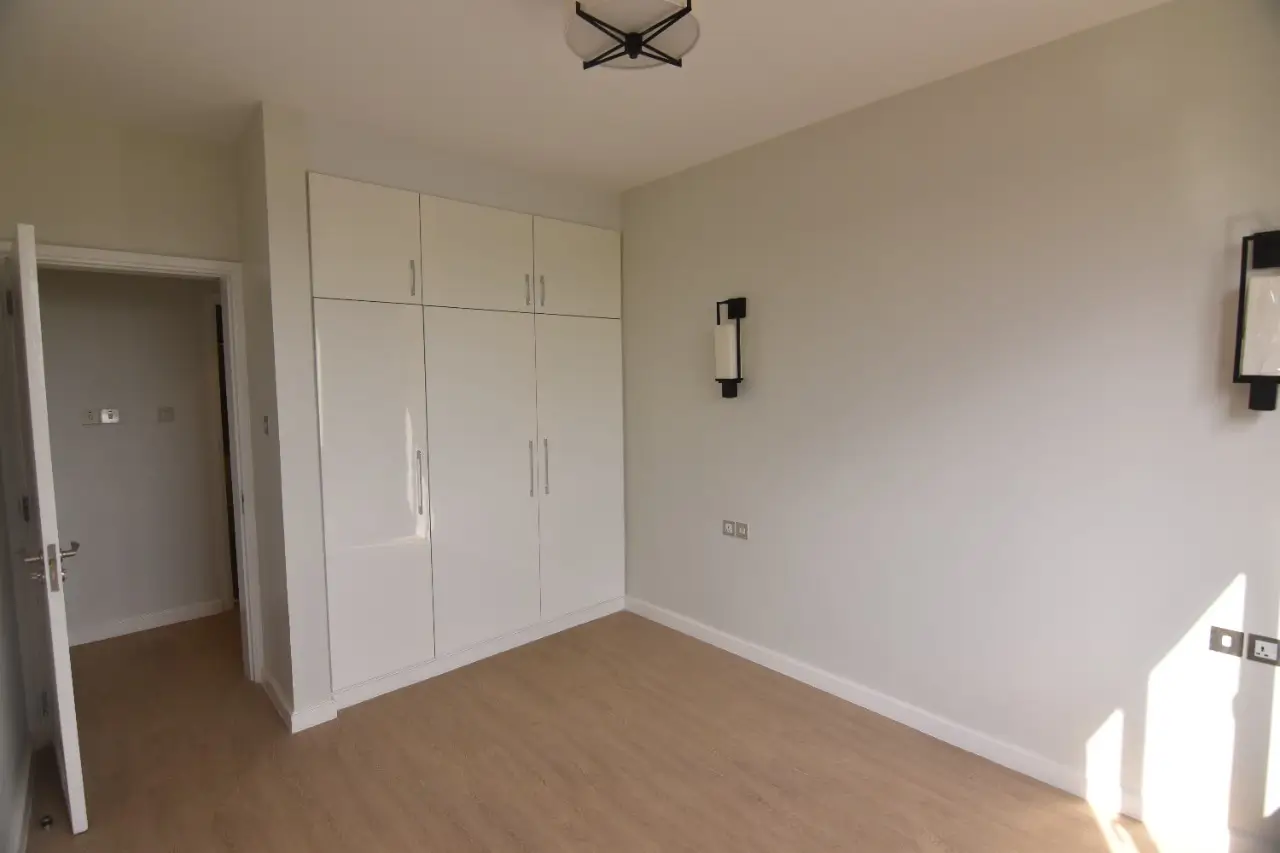 Bedroom with built-in white wardrobes and wooden flooring