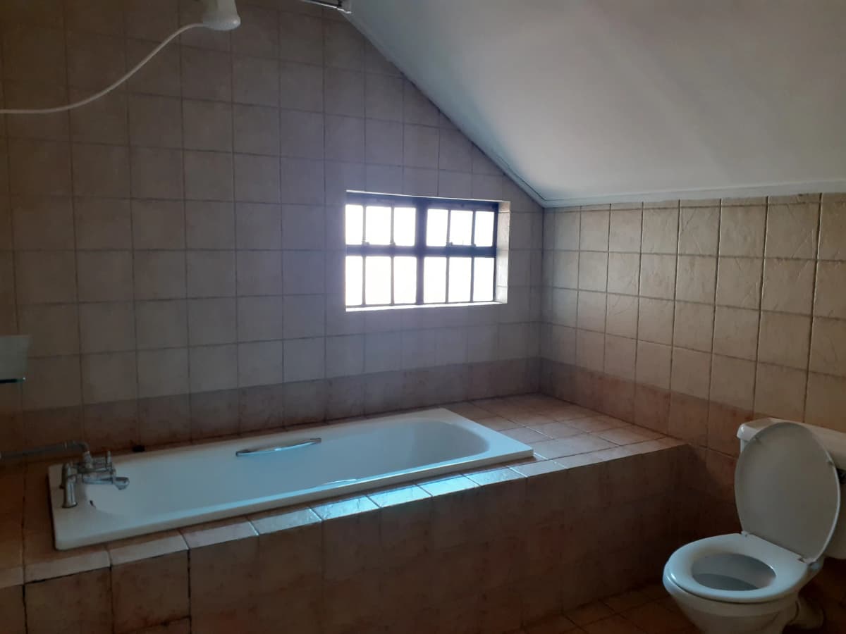 Spacious bathroom with bathtub, toilet, and natural light