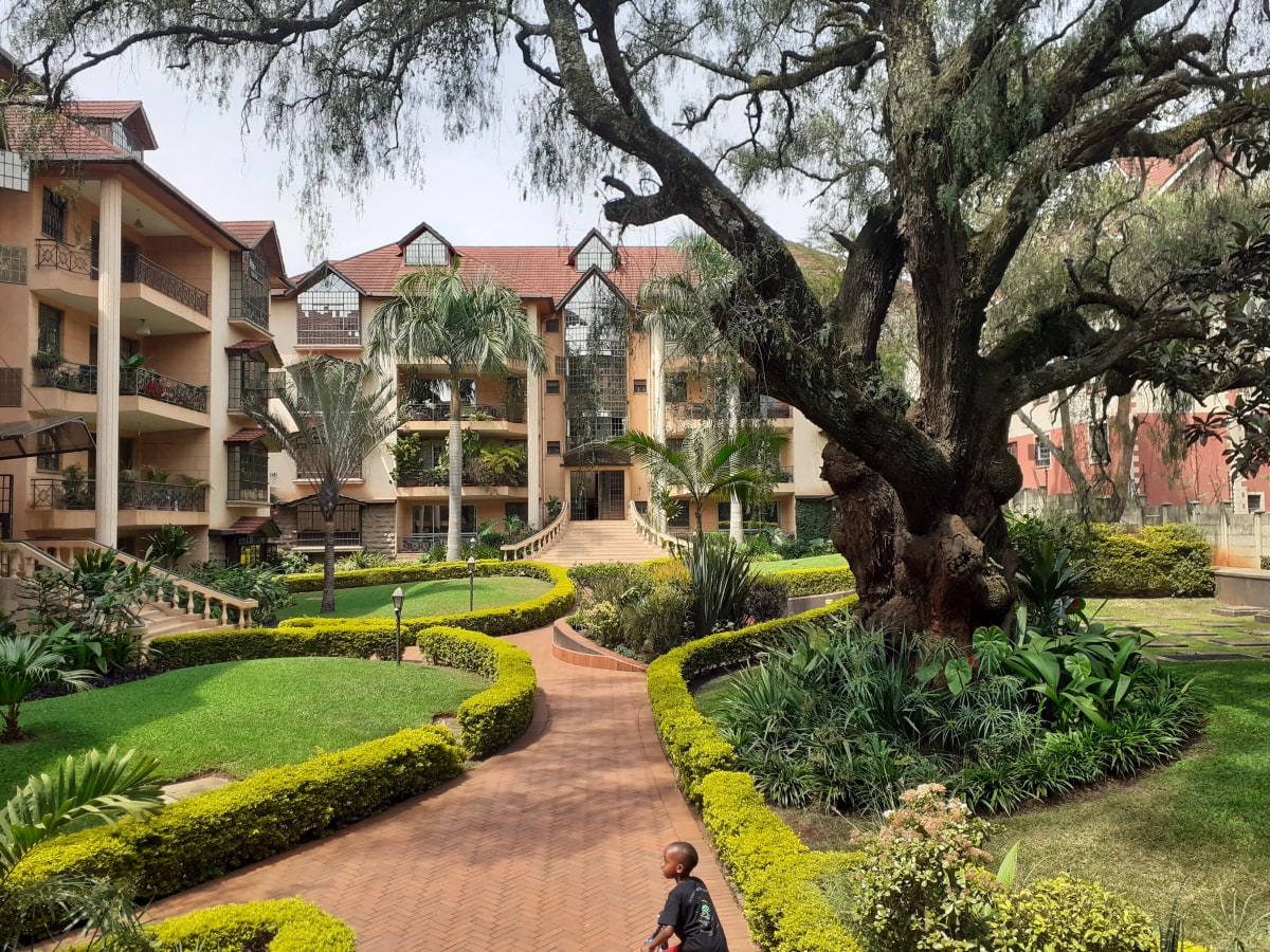 Manicured compound grounds with mature trees and landscaped pathways
