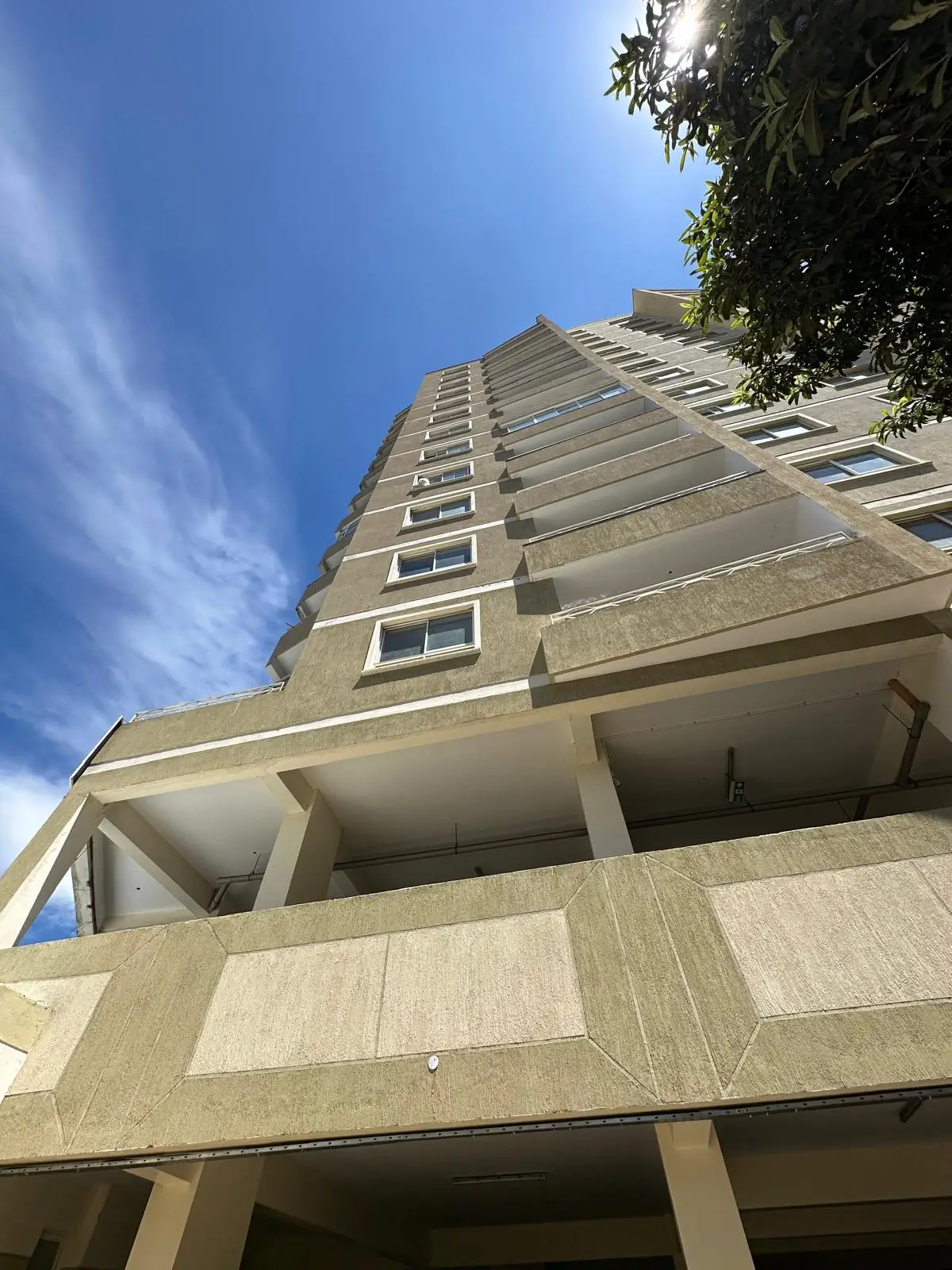 Multi-story residential building facade with balconies, shot upward