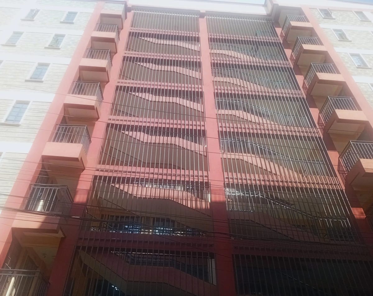 Red-brick residential building facade with metal balcony railings