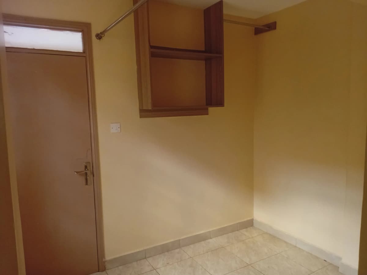 Compact kitchen with wall-mounted wooden cabinets, cream walls