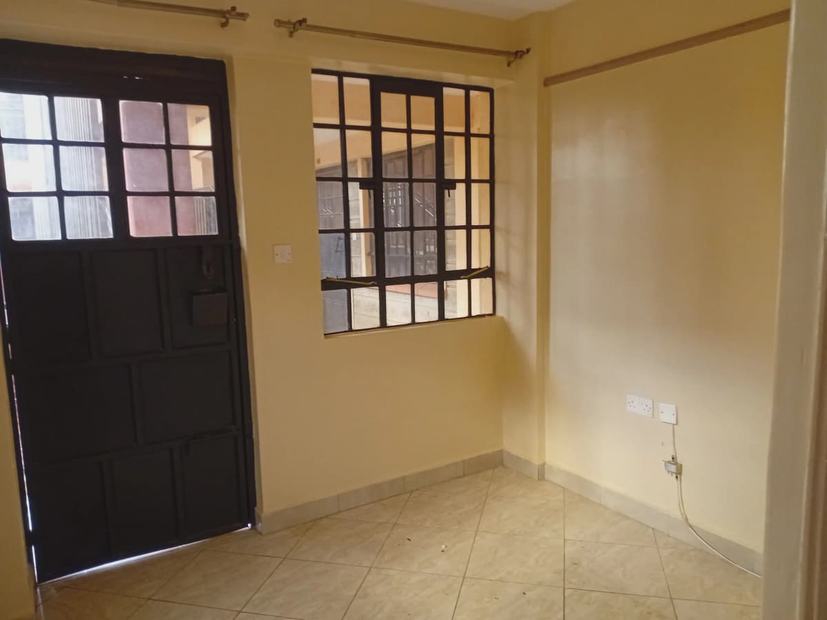 Empty living space with tiled floor and barred window